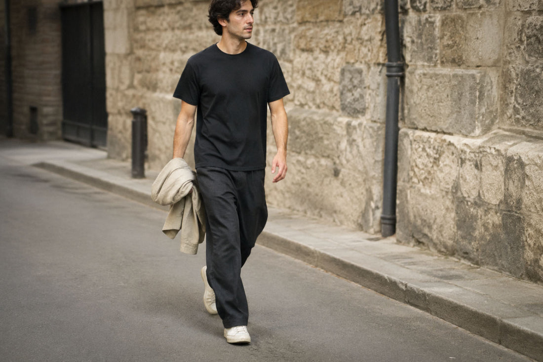 Man in a black T-shirt and dark trousers walking down a street, with the T-shirt hem visible