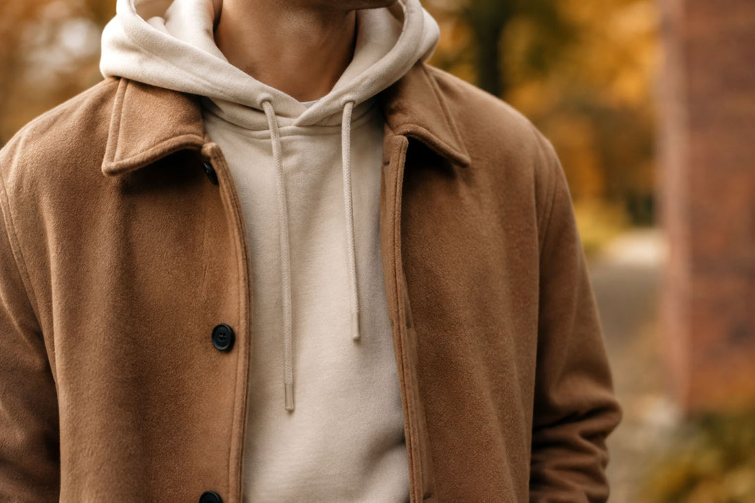 Ivory hoodie layered under an open camel jacket, clean silhouette — minimalist cold weather layering, Biliping